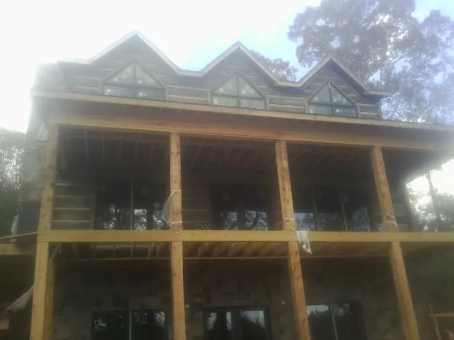 Dormers and porch framing on a large log home under construction — Roof Coating work by our crew in Oysterville