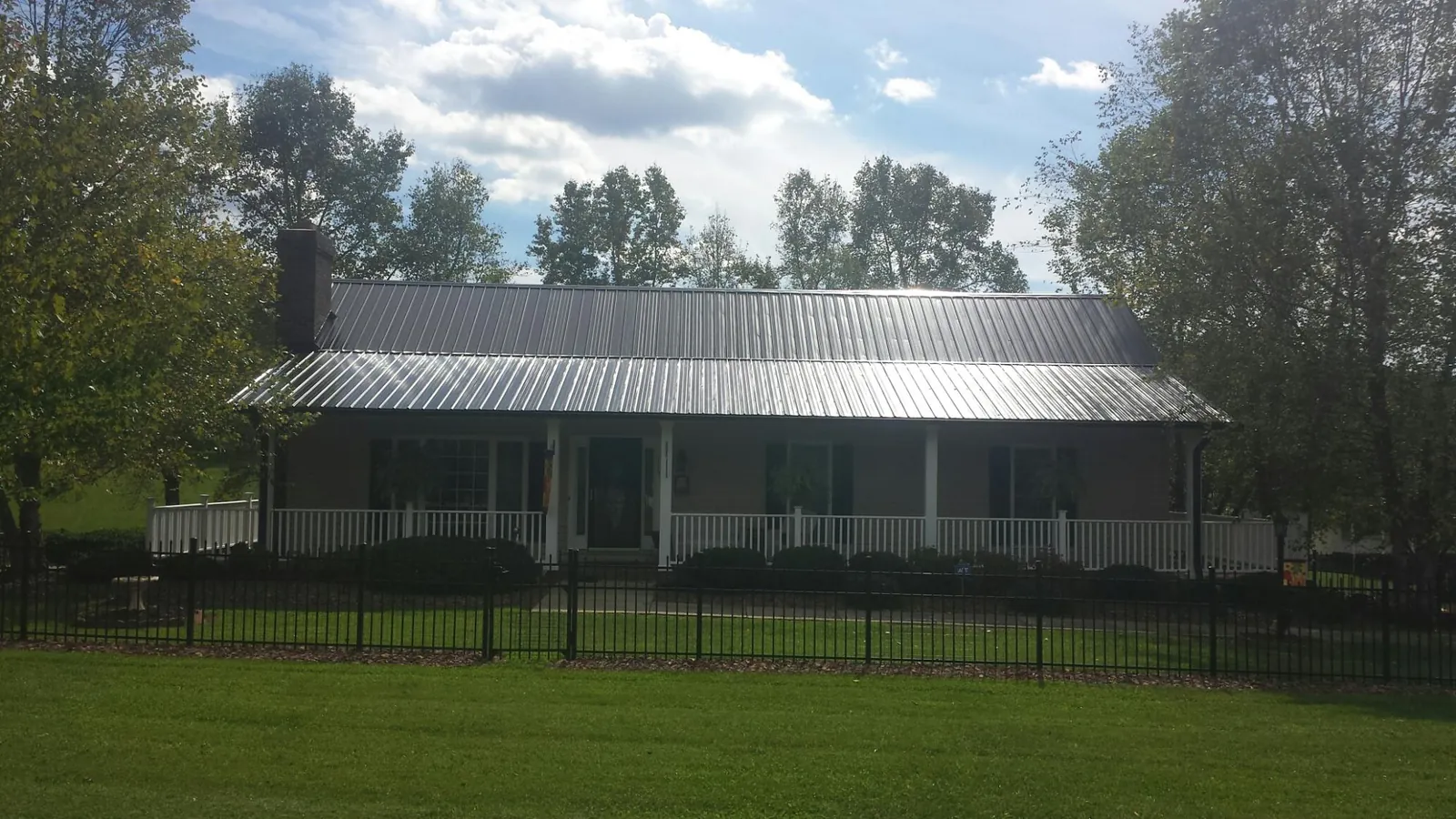 Gray metal roof on a brick ranch with a full width front porch — Gutter Guard Installation work by our crew in Oysterville