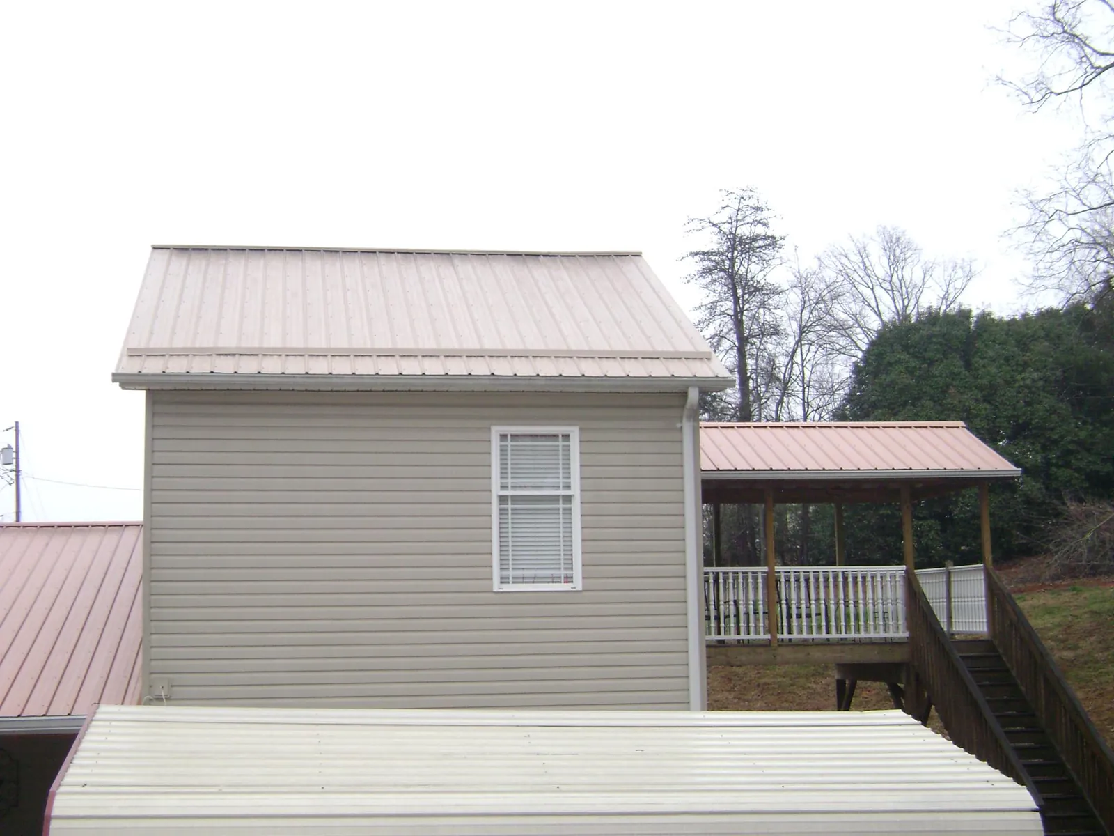 Tan metal roofs on a two story addition and attached porch, from a Roof Replacement job in Oysterville