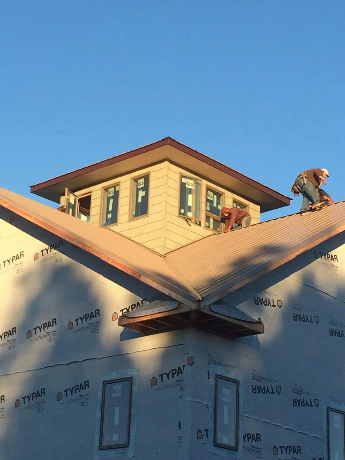 Roofers working around a rooftop cupola on a new metal roof at sunset — Roof Waterproofing in Oysterville by Roofing Brothers